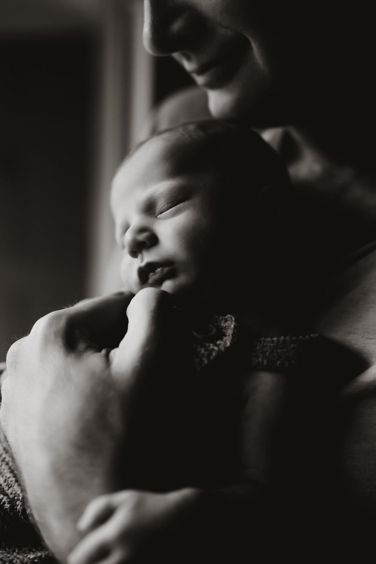 lifestyle newborn photo session of a father cuddling  his baby boy