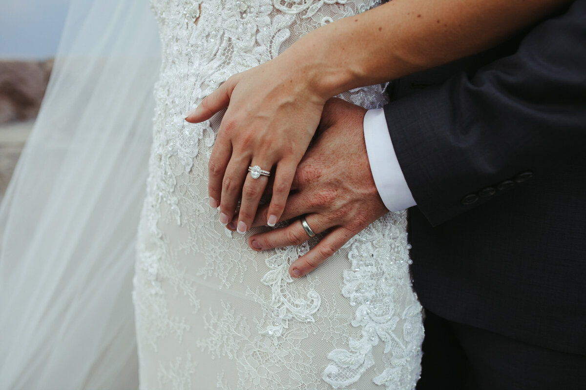 Close up of wedding rings on a lace wedding dress.