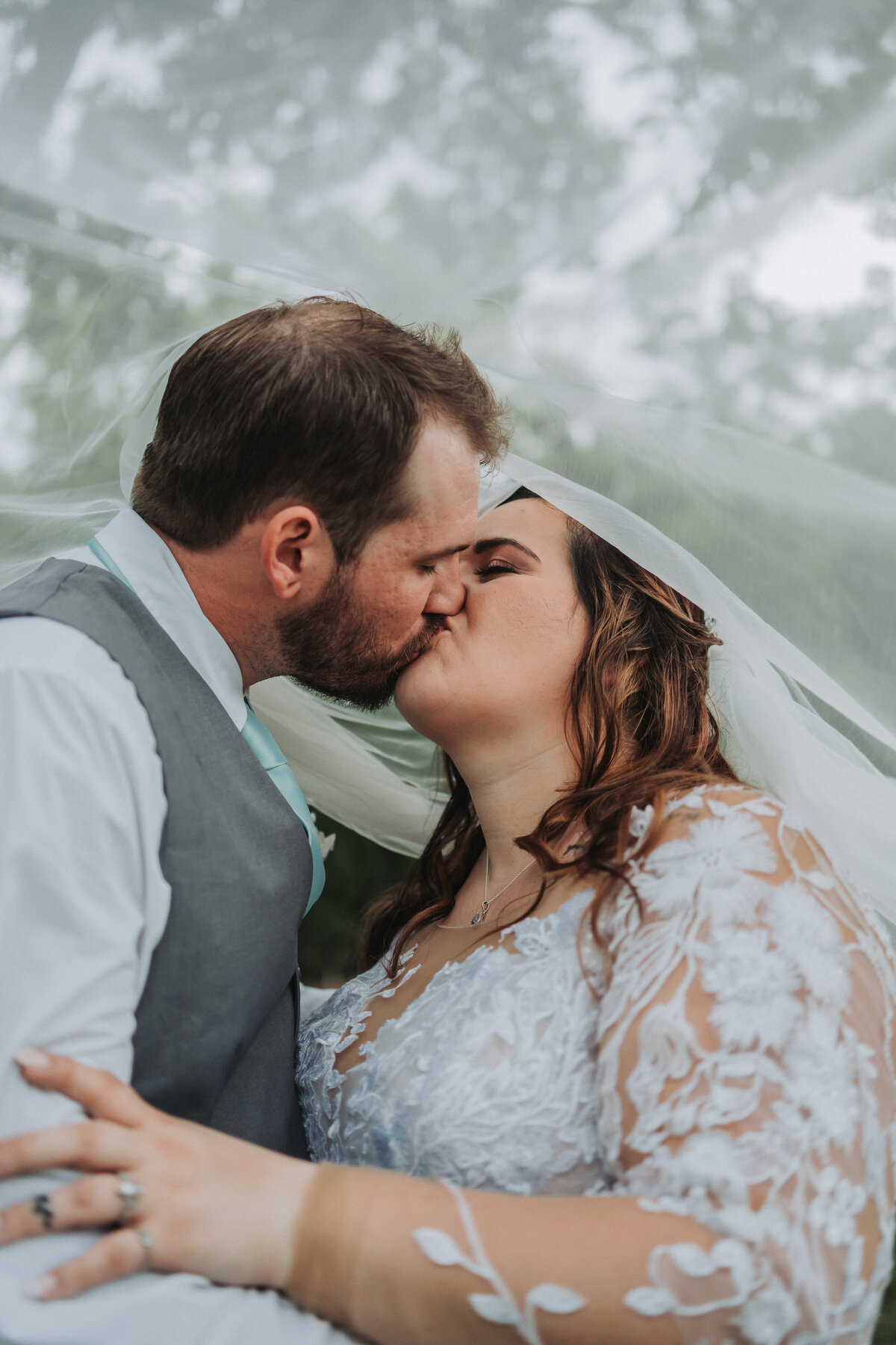 A newlywed couple shares a tender kiss, with the bride's veil gently draped around them, creating an intimate moment during their Virginia wedding, captured by Quinn Photography LLC.