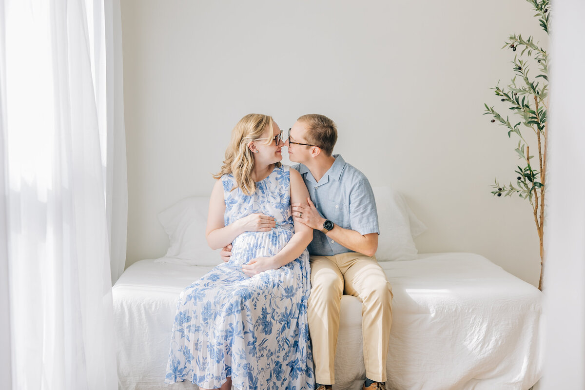 couple sitting on bed next to a window