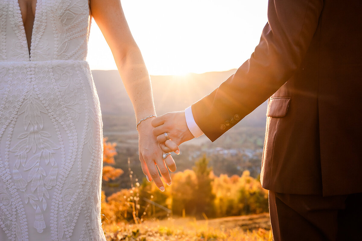 Bride and groom holding pinkies during fall sunset at Cranmore Mountain Summit wedding in North Conway NH