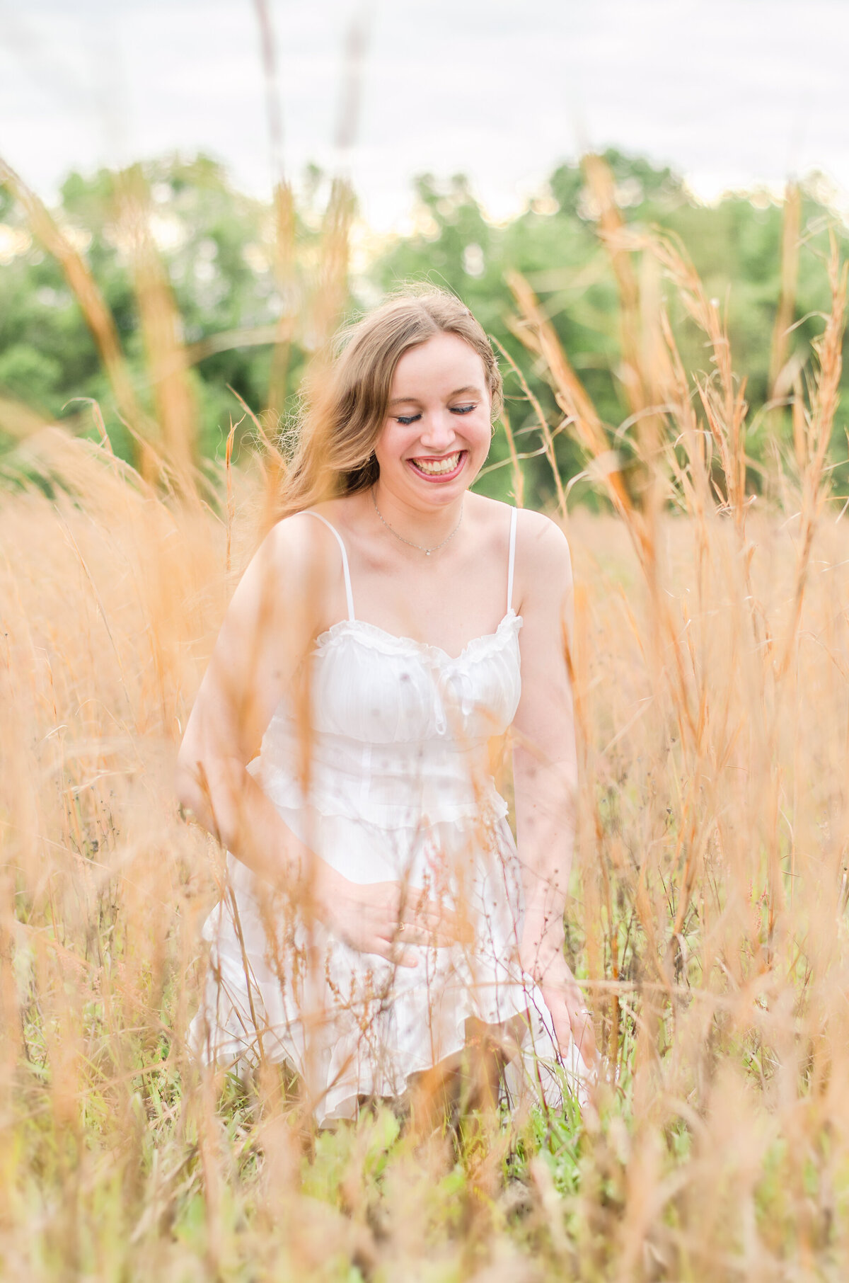 woman laughs in wheat field at sunset