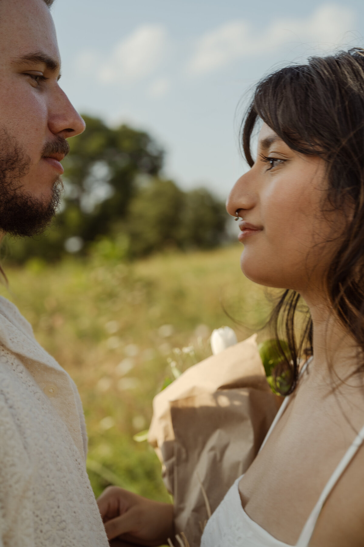 A heartfelt close-up of a couple gazing into each other's eyes, taken in the picturesque park near White Rock Lake in Dallas.