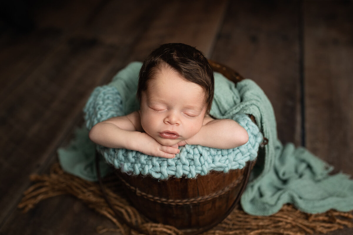 Newborn boy in wooden bucket.