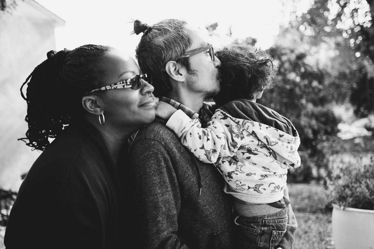 Black & white photo of a family embracing each other outside during their los angles photoshoot.