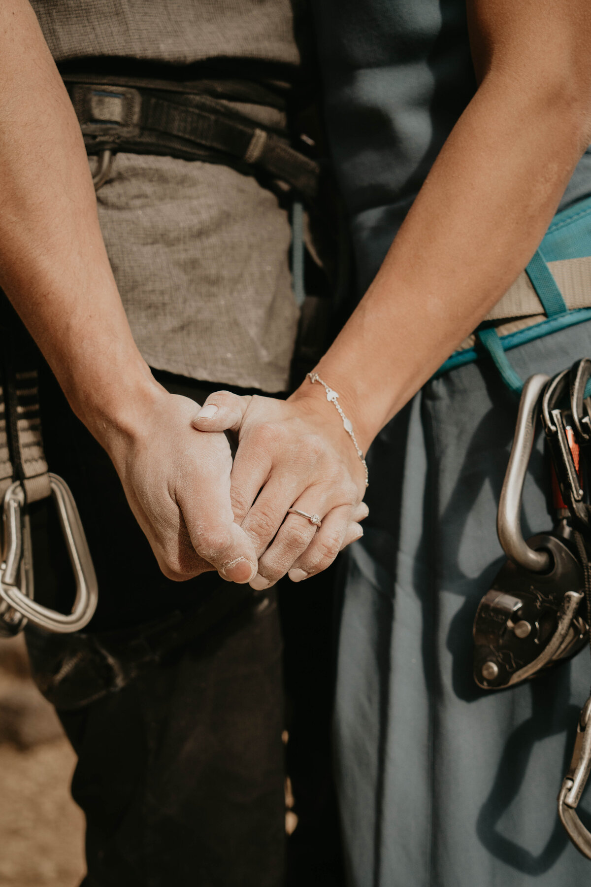 Close up photo of rock climbing engagement couple holding chalky hands