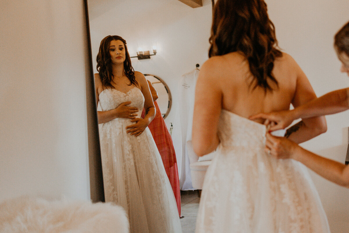 bride and her mom getting  in her wedding dress