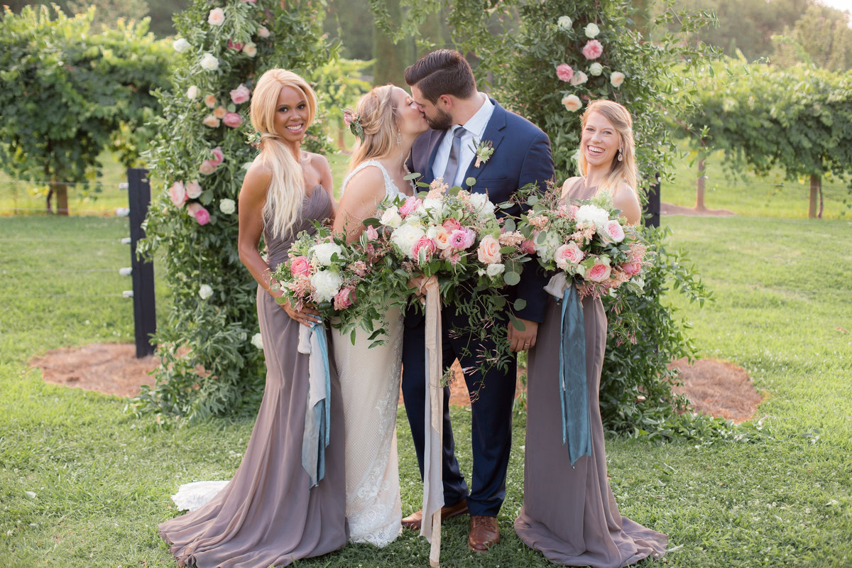 wedding photographer captures bride and groom first kiss in outdoor vineyard