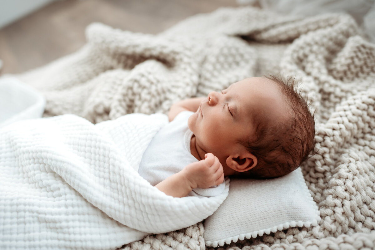 newborn boy lying in blankets on pillow