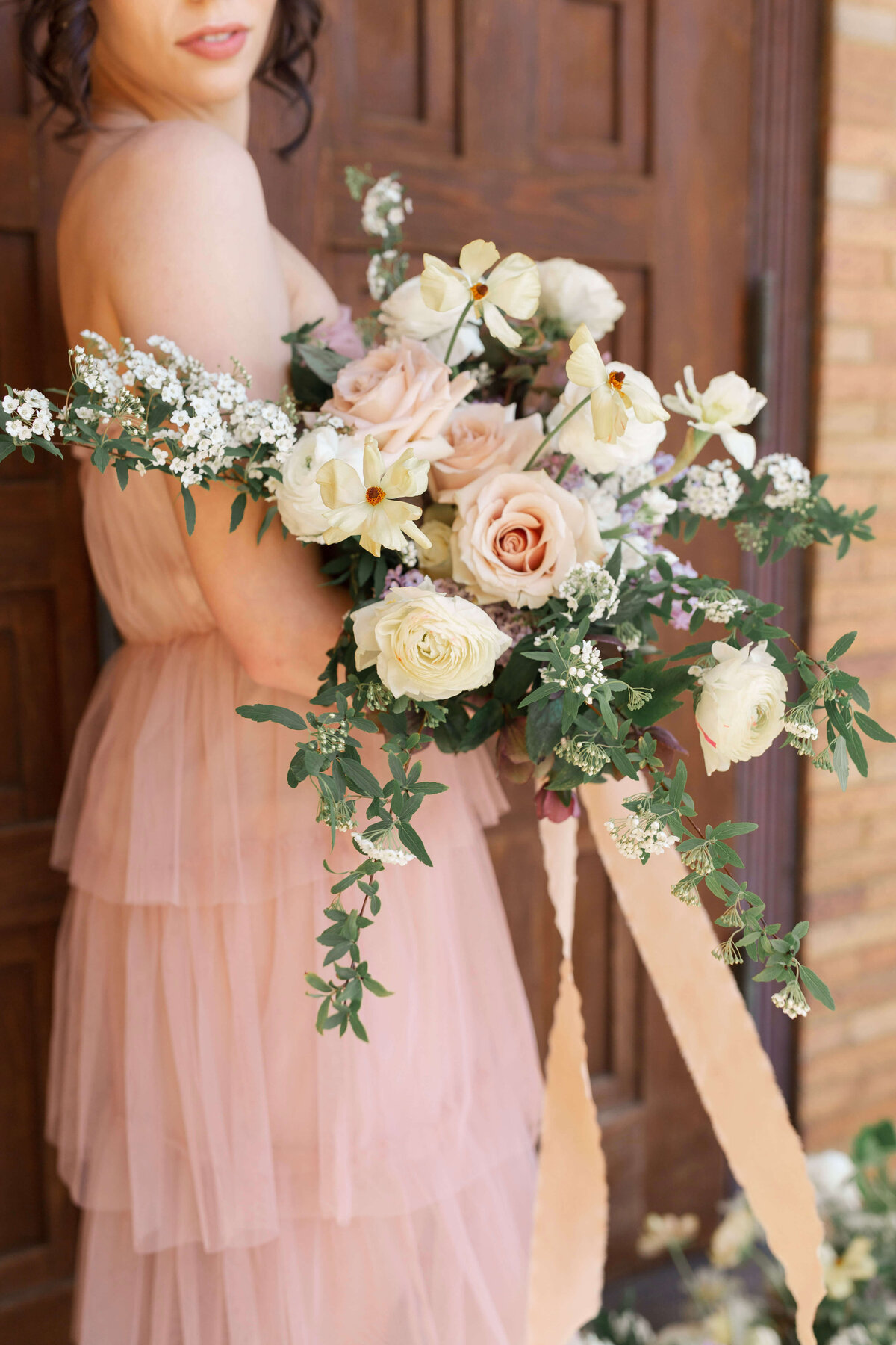 woman holding large bouquet of flowers in ivory, peach, pale pink, lavender and greenery
