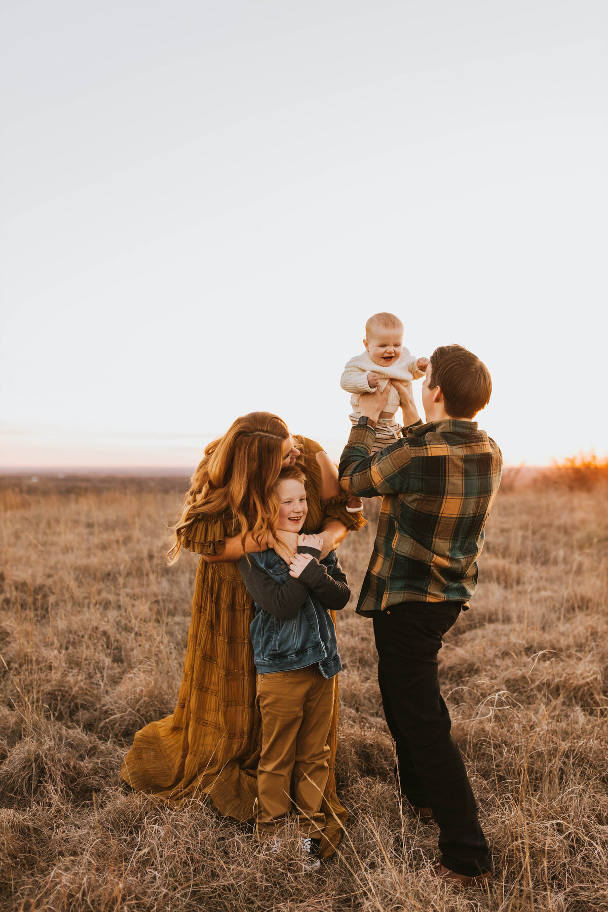 Family of four playing in a field during golden hour