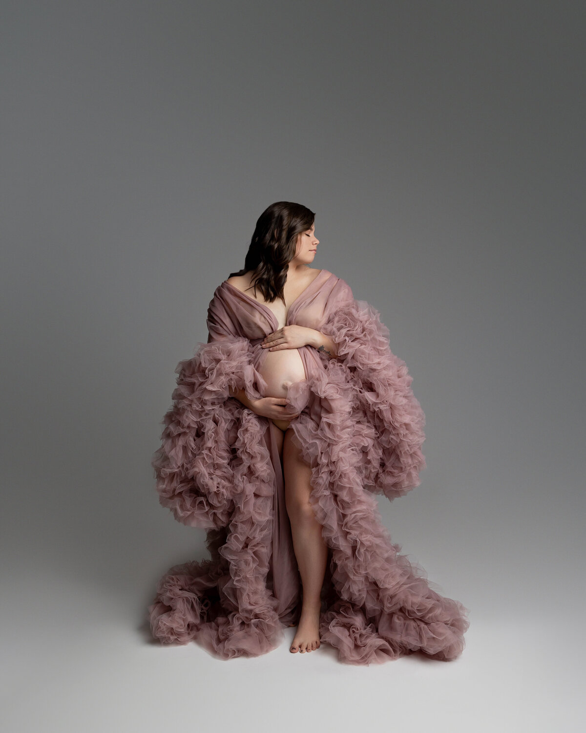 Wearing a soft pink ruffle dress, she poses in a side view with her face gently turned, the delicate layers of the dress adding movement and softness to the shot. Captured by Inland Empire photographer Kaitlyn Dawn Photography.