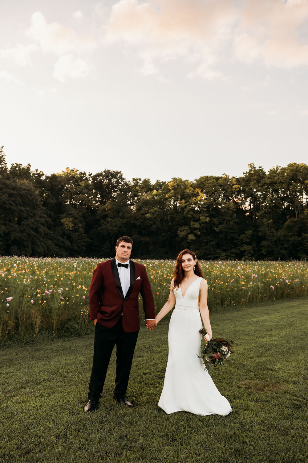 Bride and groom holding hands in a wildflower field, bride in a white gown