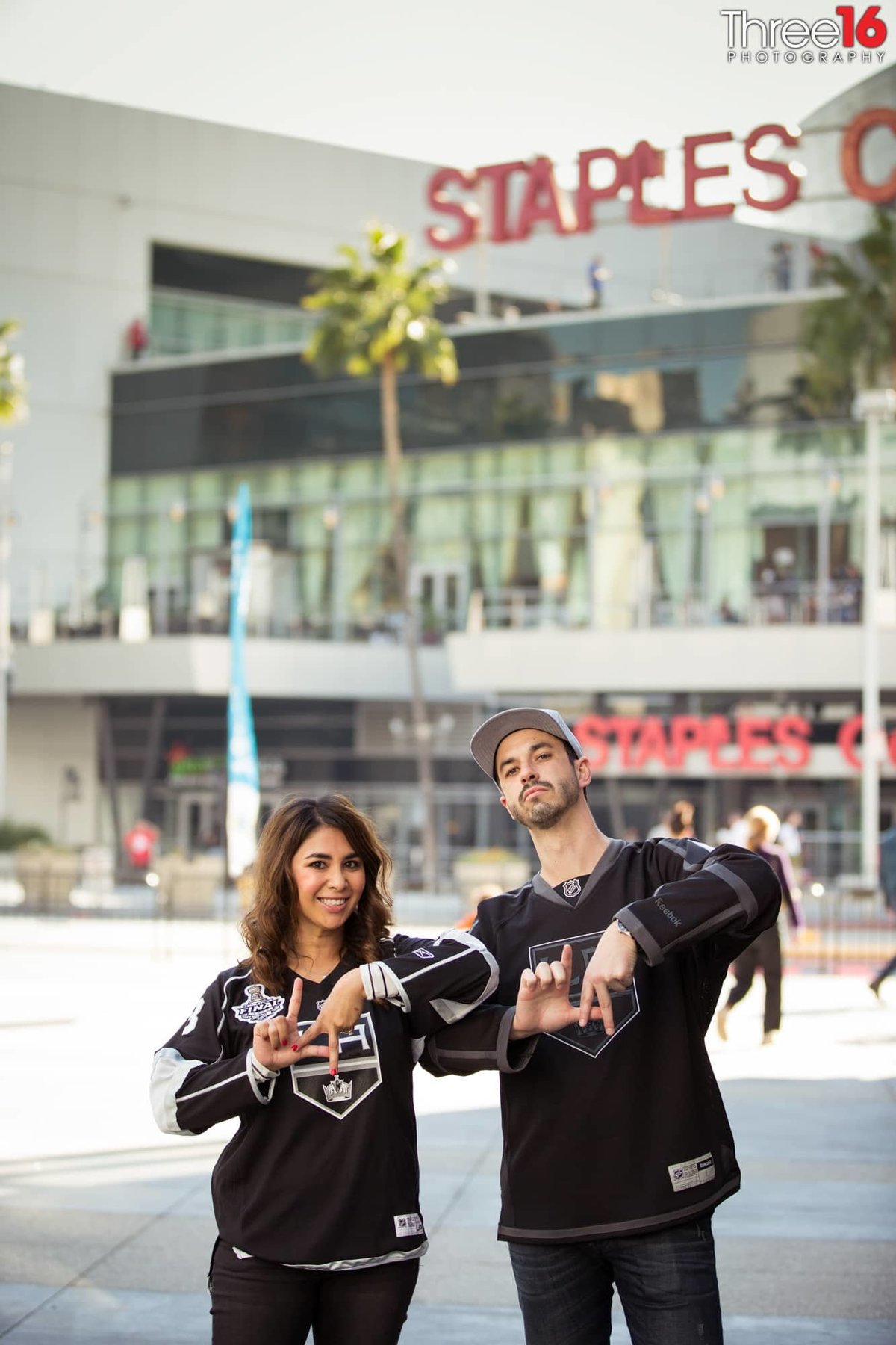Engaged couple give the LA hand sign in front of the Staples Center