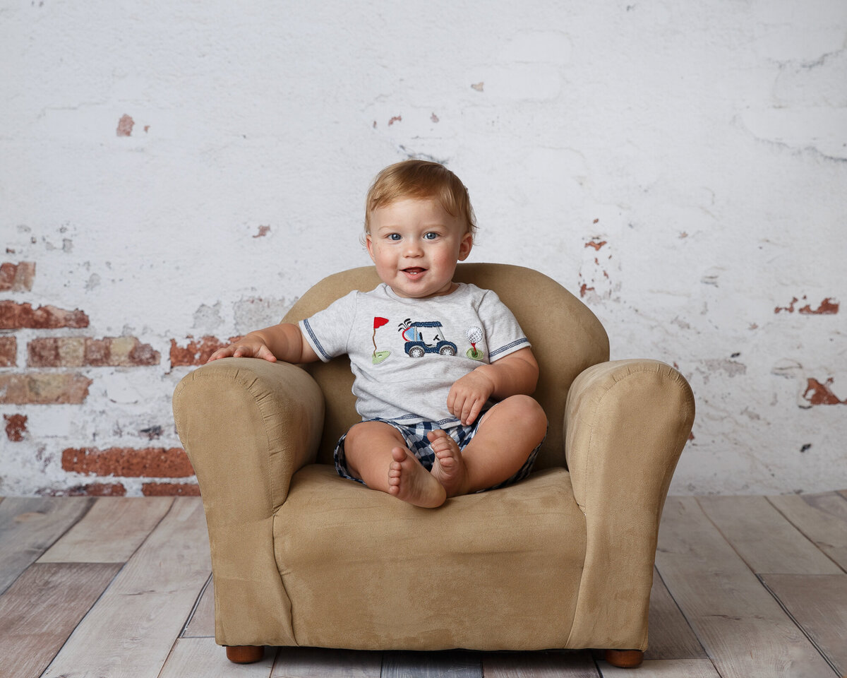Milestone portrait of a cute toddler boy sitting on a little child size chair