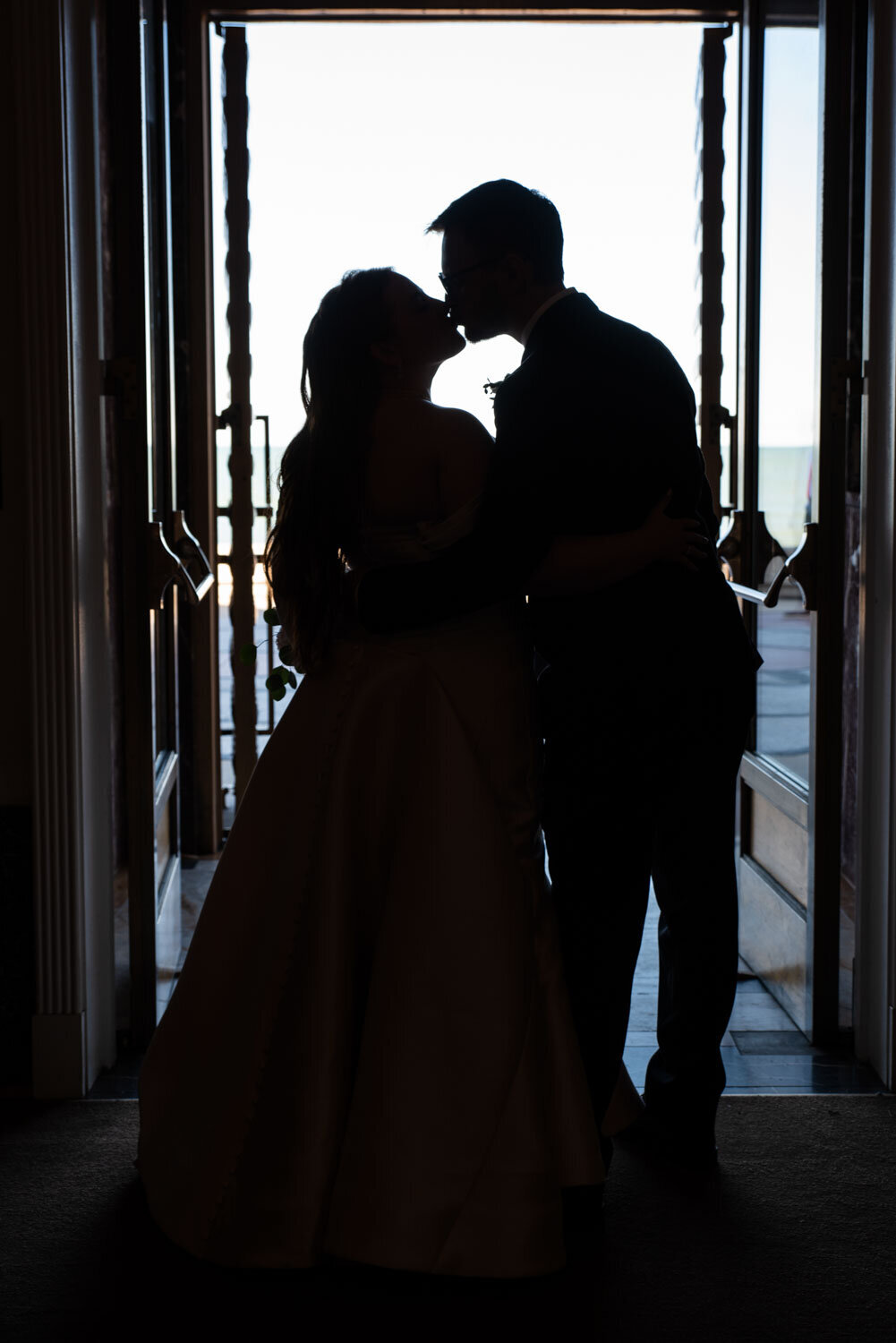 A silhouette of a bride and groom kissing in a doorway
