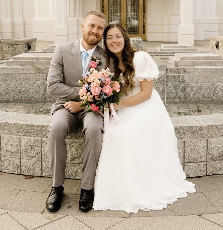 bride-and-groom-sitting-together-outside-lds-temple-with-bridal-bouquet