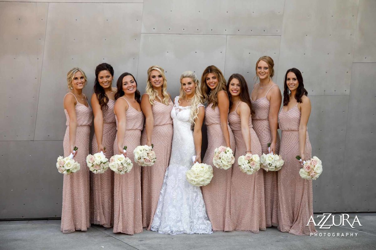 Beautiful bridal party at the Four Seasons Seattle wearing long blush dresses and holding round, white rose bouquets