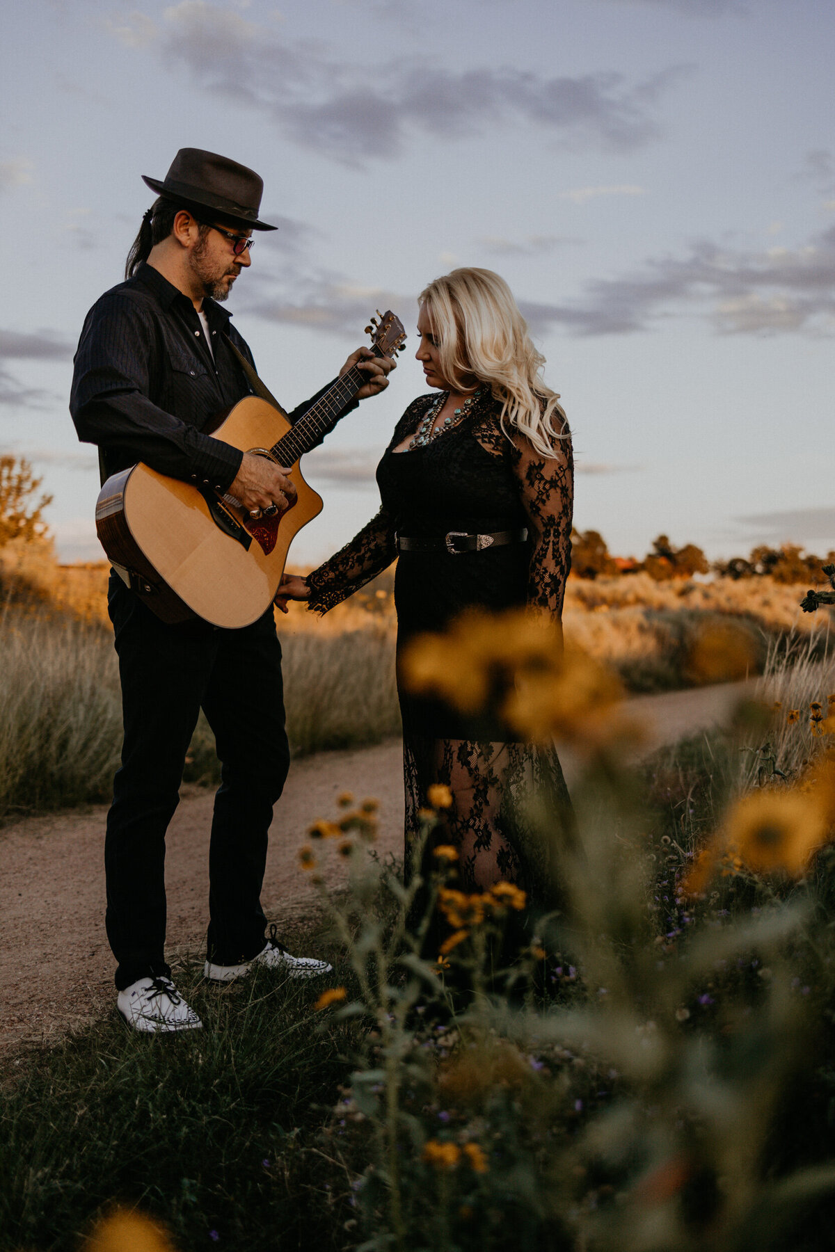 engaged couple holding hands with a guitar in Santa Fe