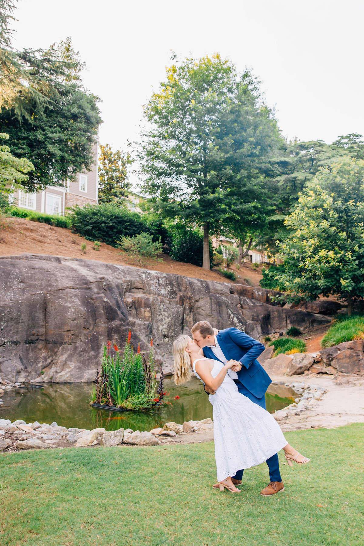 couple dipping holding each other in front of rock wall with florals in the background
