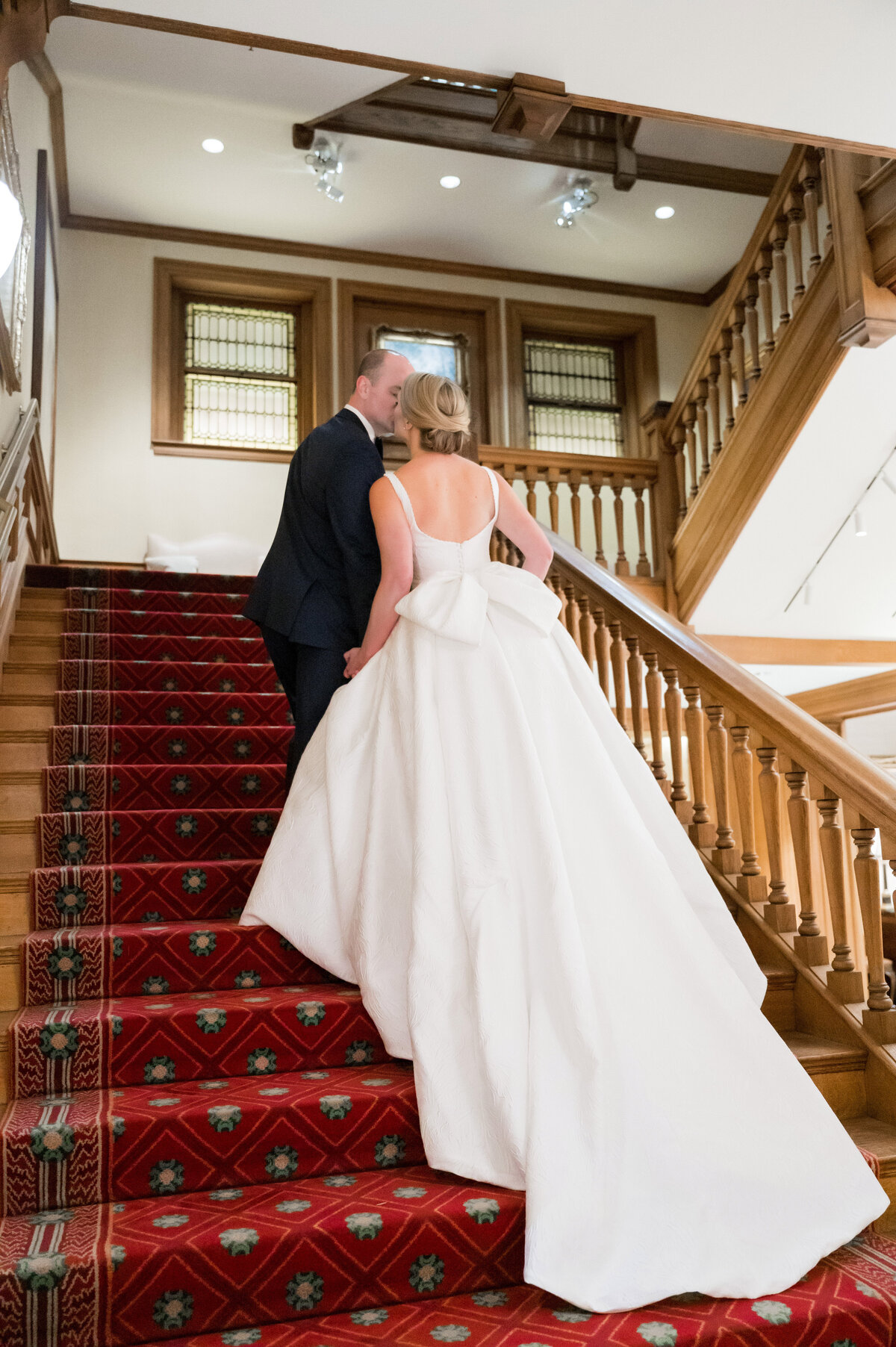 bride and groom kissing as they walk up the grand staircase of duquesne club