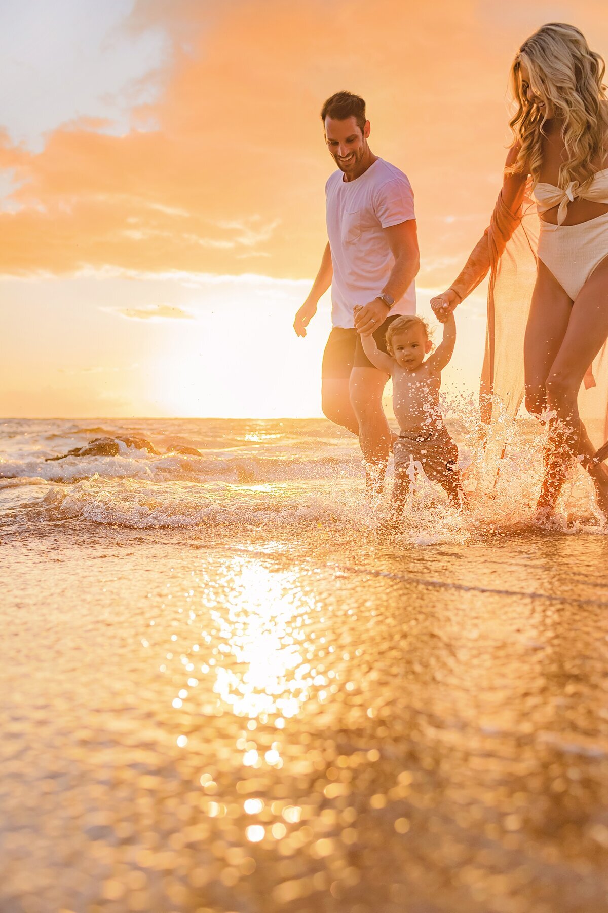 Family holding hands and walking on Wailea Beach with family portraits by Love + Water