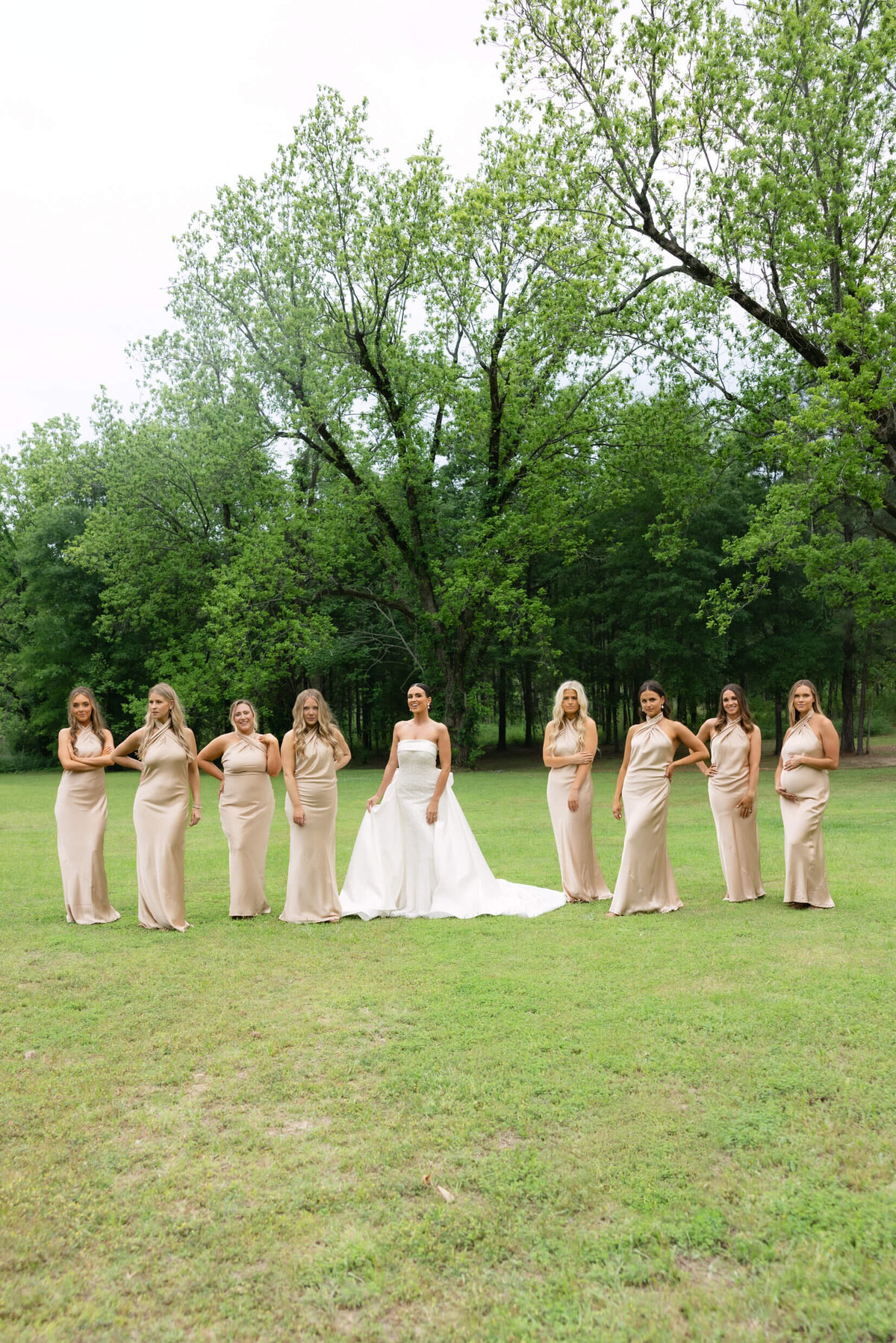 A wedding day portrait photo of the bride in her white wedding dress surrounded by her bridesmaids