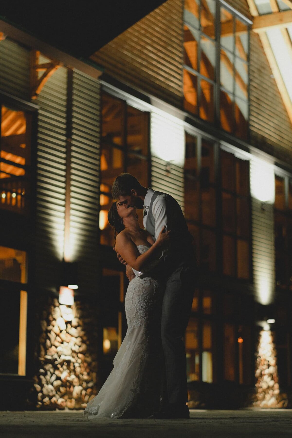 Wedding couple kiss in front of Mount Norquay Ski Lodge in Banff