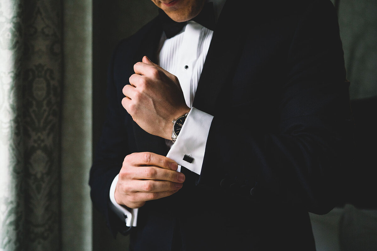 The groom is getting ready and adjusting his cufflinks