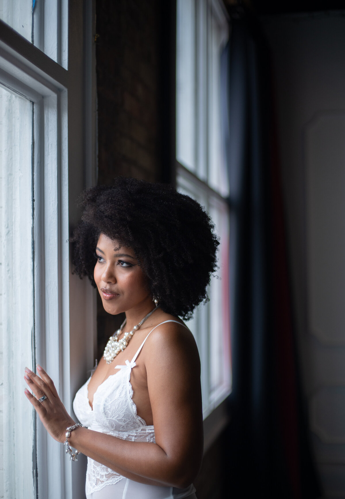 Bridal boudoir session featuring a bride in white lingerie at the window