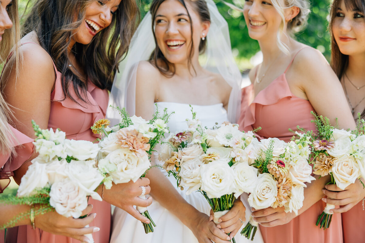 Bride smiling with her bridesmaids while holding their wedding bouquets for a wedding picture in Coeur d'Alene