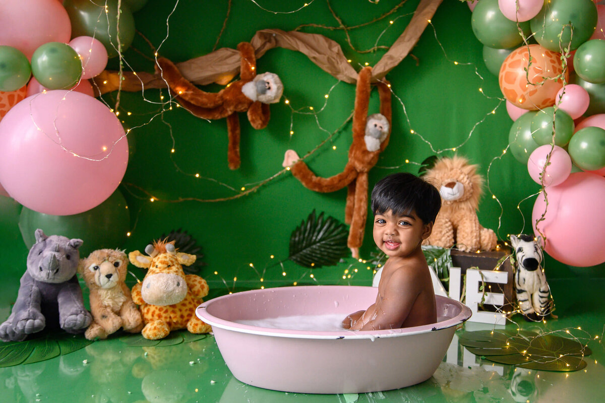 Little girl in a pink tub for her jungle themed cake smash photographer session in Burlington, Ontario