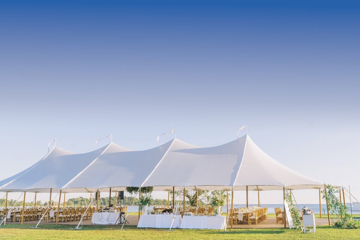 A pole marquee next to a buulding with an orangery attached.