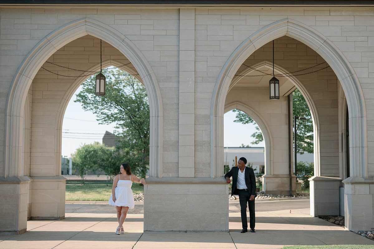Engagement photo of couple framed under elegant stone arches in Kalamazoo, Michigan.