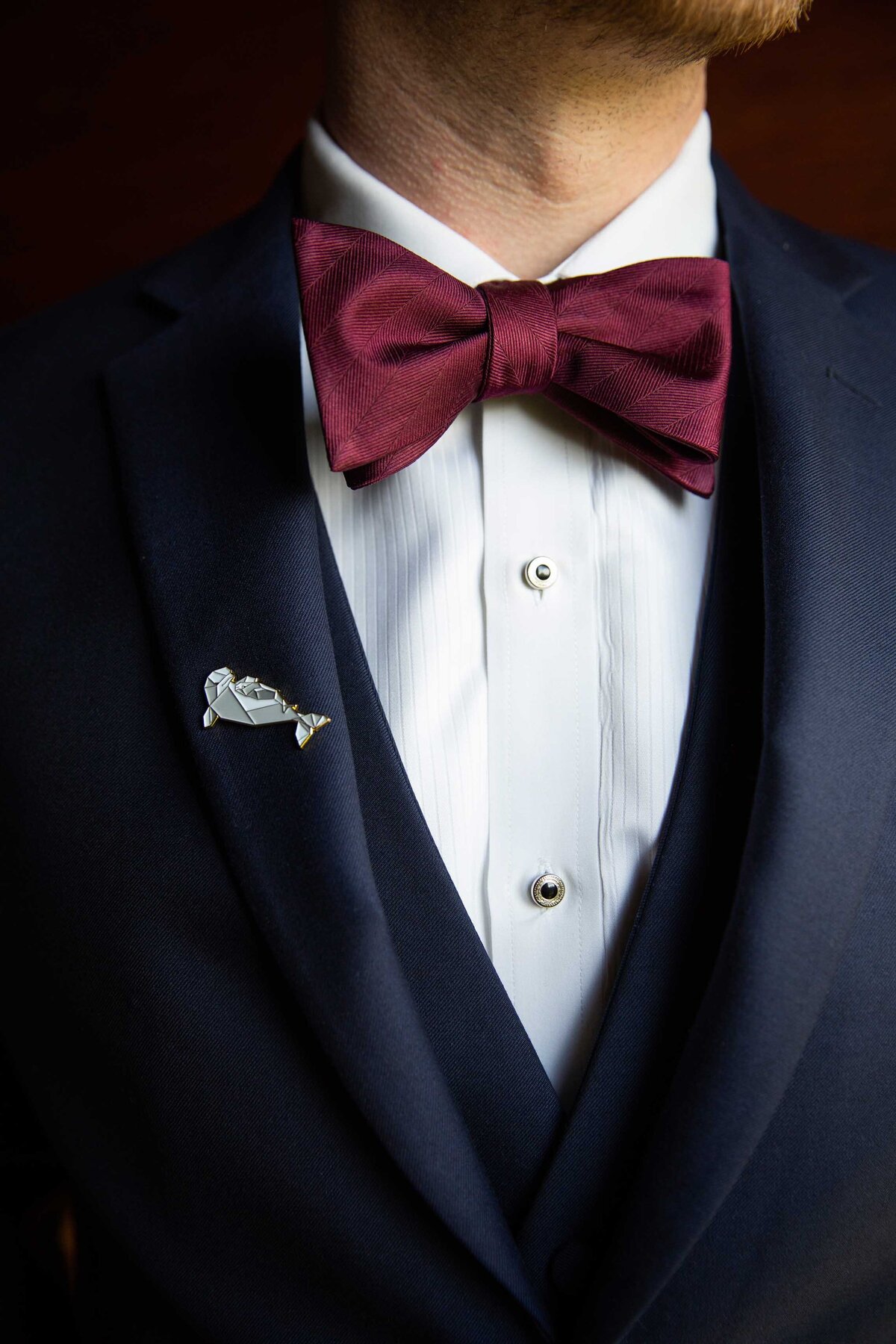 Dolphin pin attached to the breast of the groom.  Navy suite, detailed shot