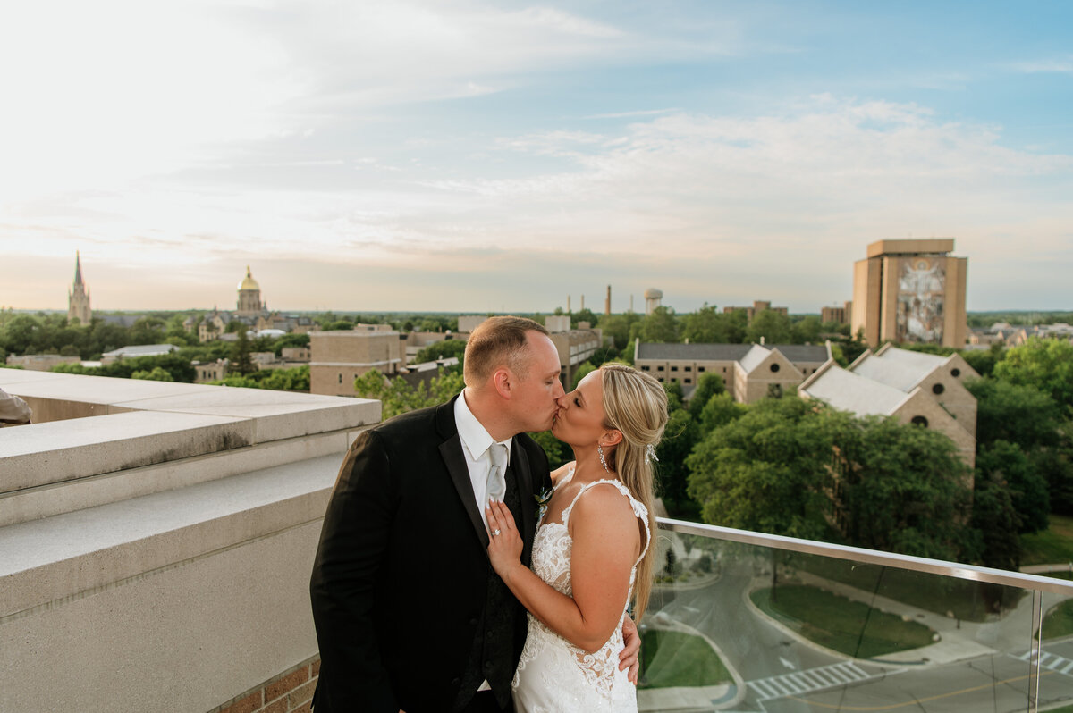 Bride and groom rooftop kiss at sunset