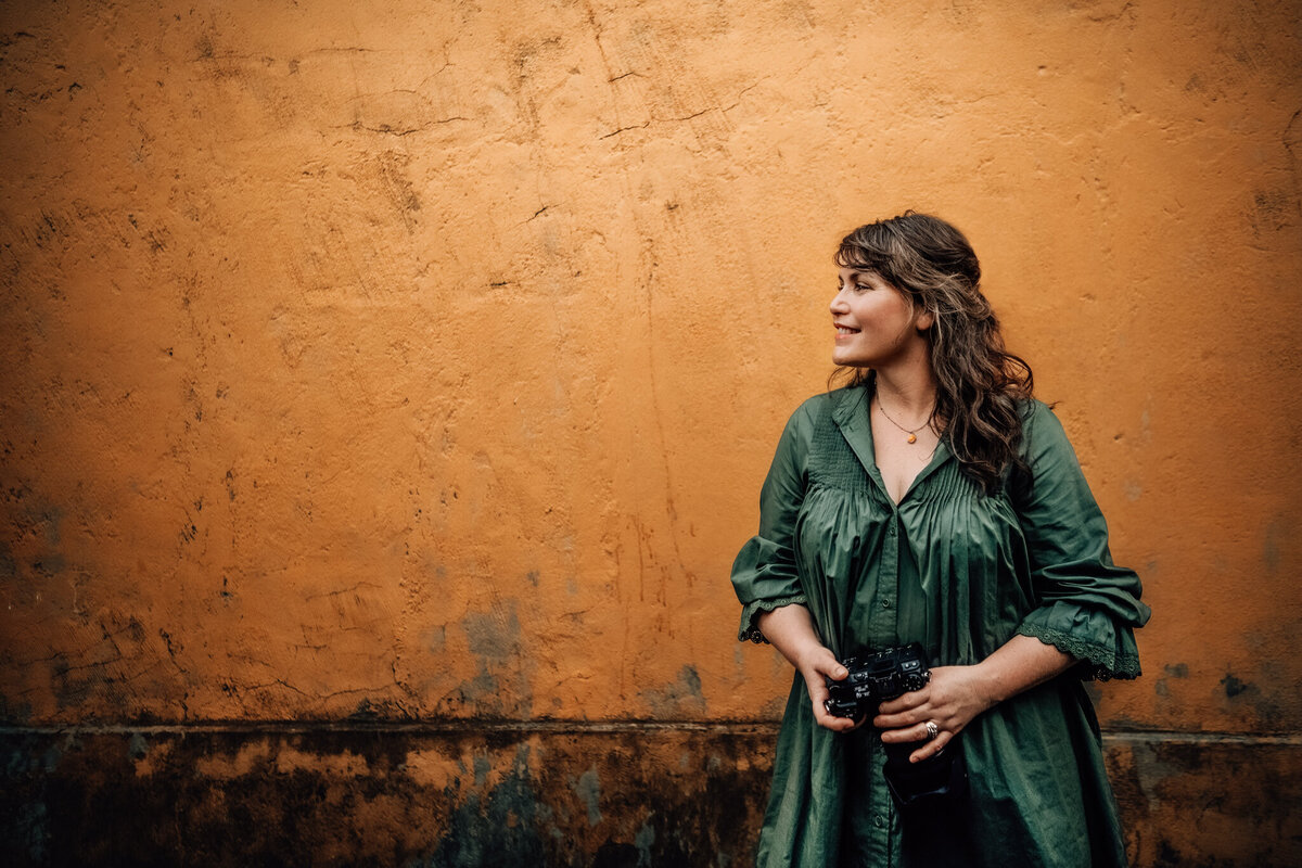 woman leaning on  a veranda holding a camera