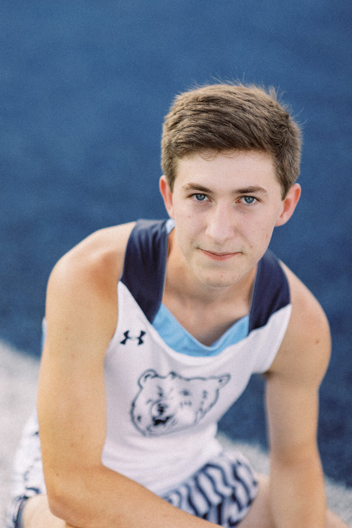 bartlesville senior boy poses at field in track uniform