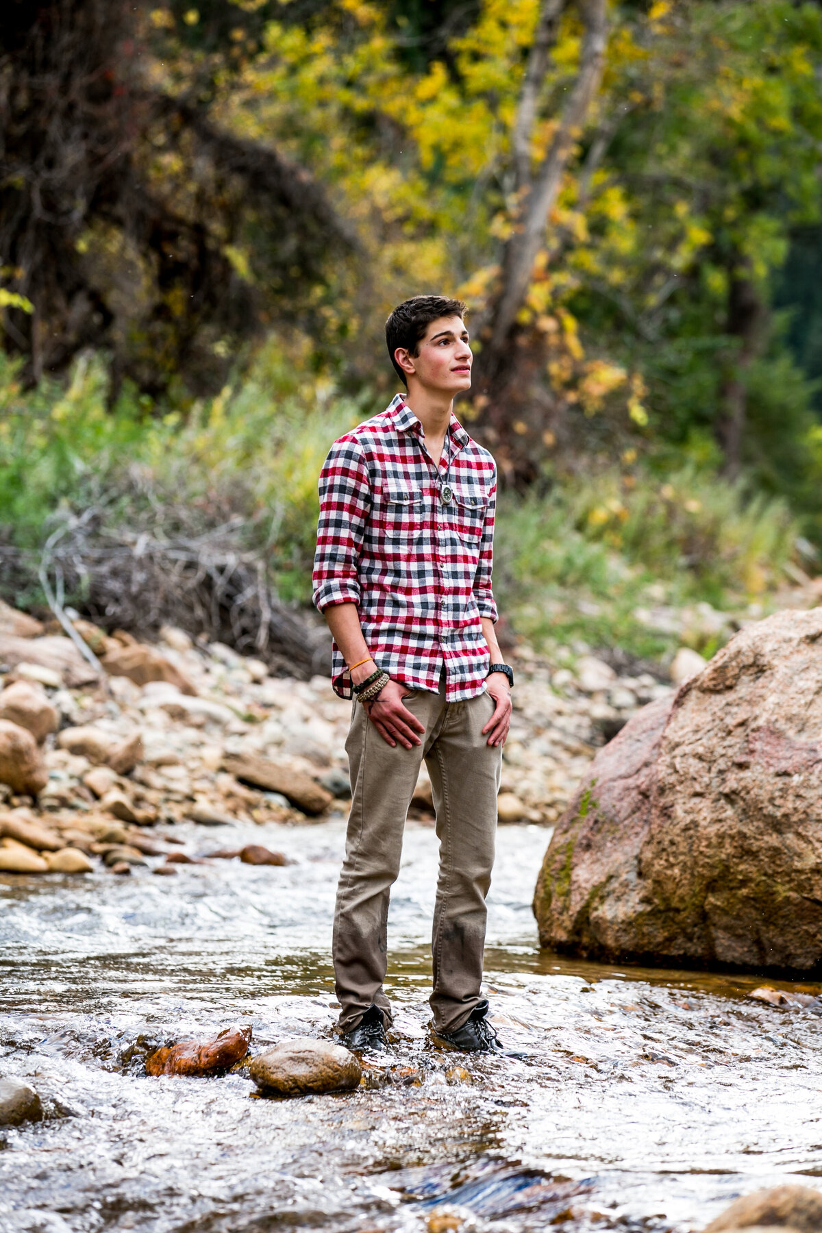 young man stands in a river for portraits