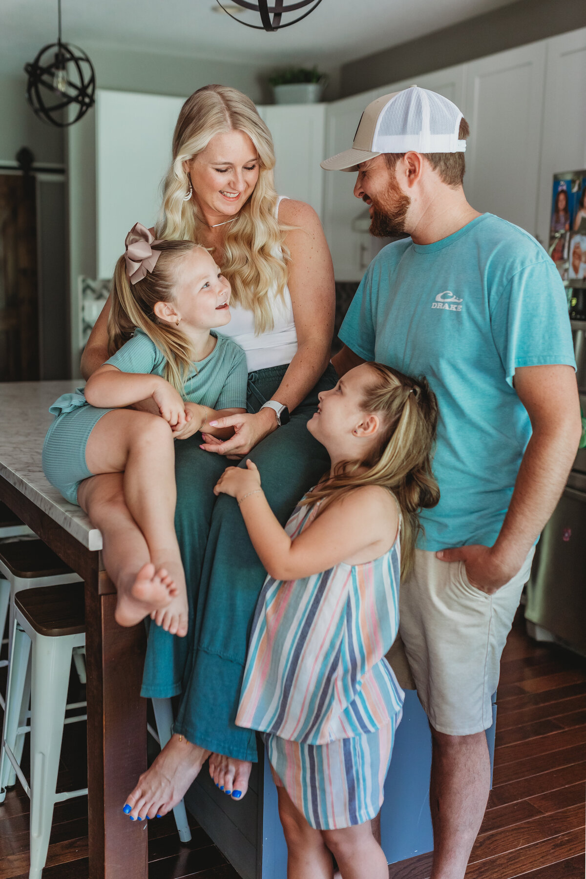 In-Home family session. In the kitchen sitting on a kitchen island. The family is all looking at each other.