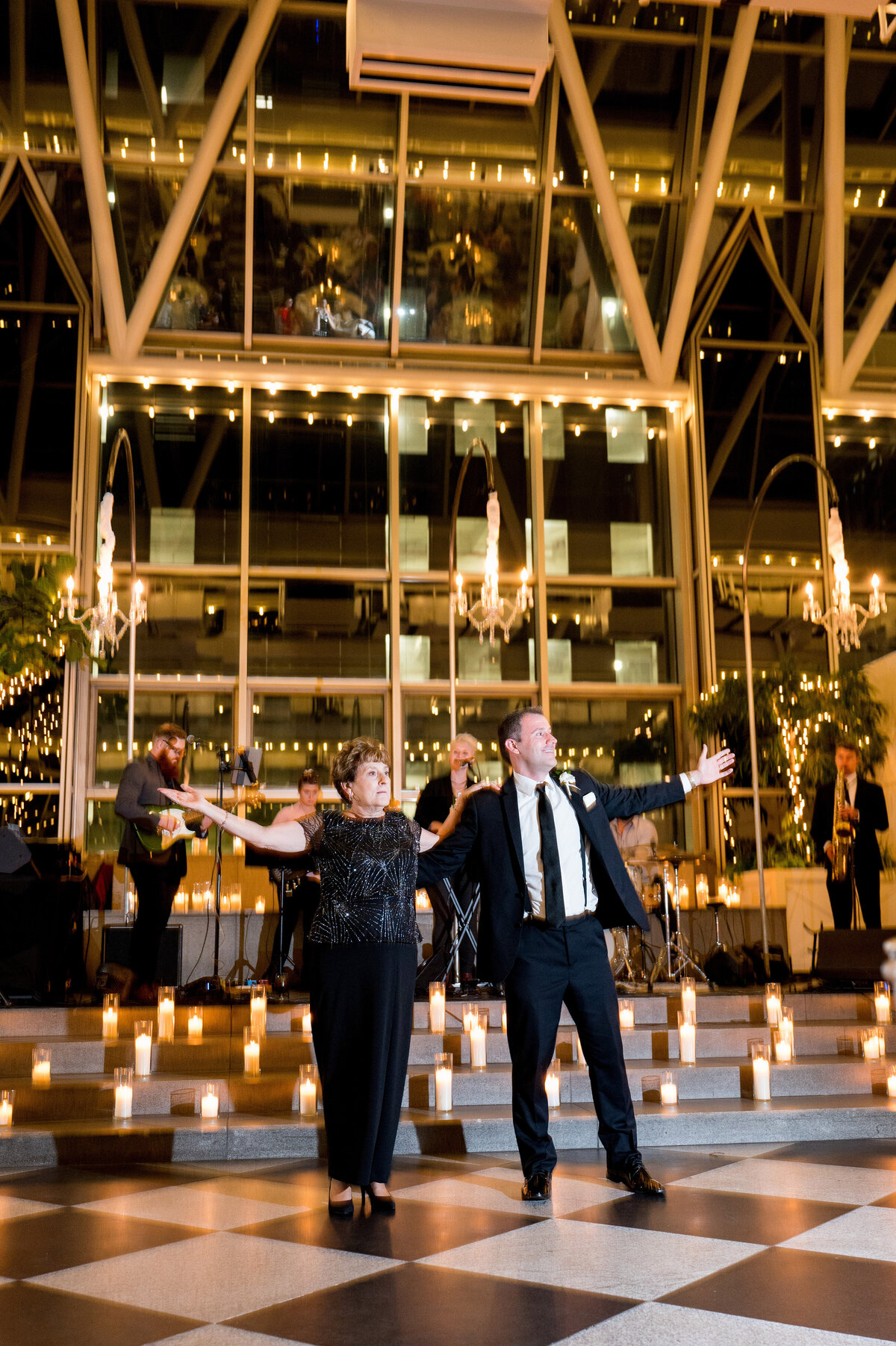 mom and son dancing together at wedding reception with lots of candles all around at wintergarden at ppg place