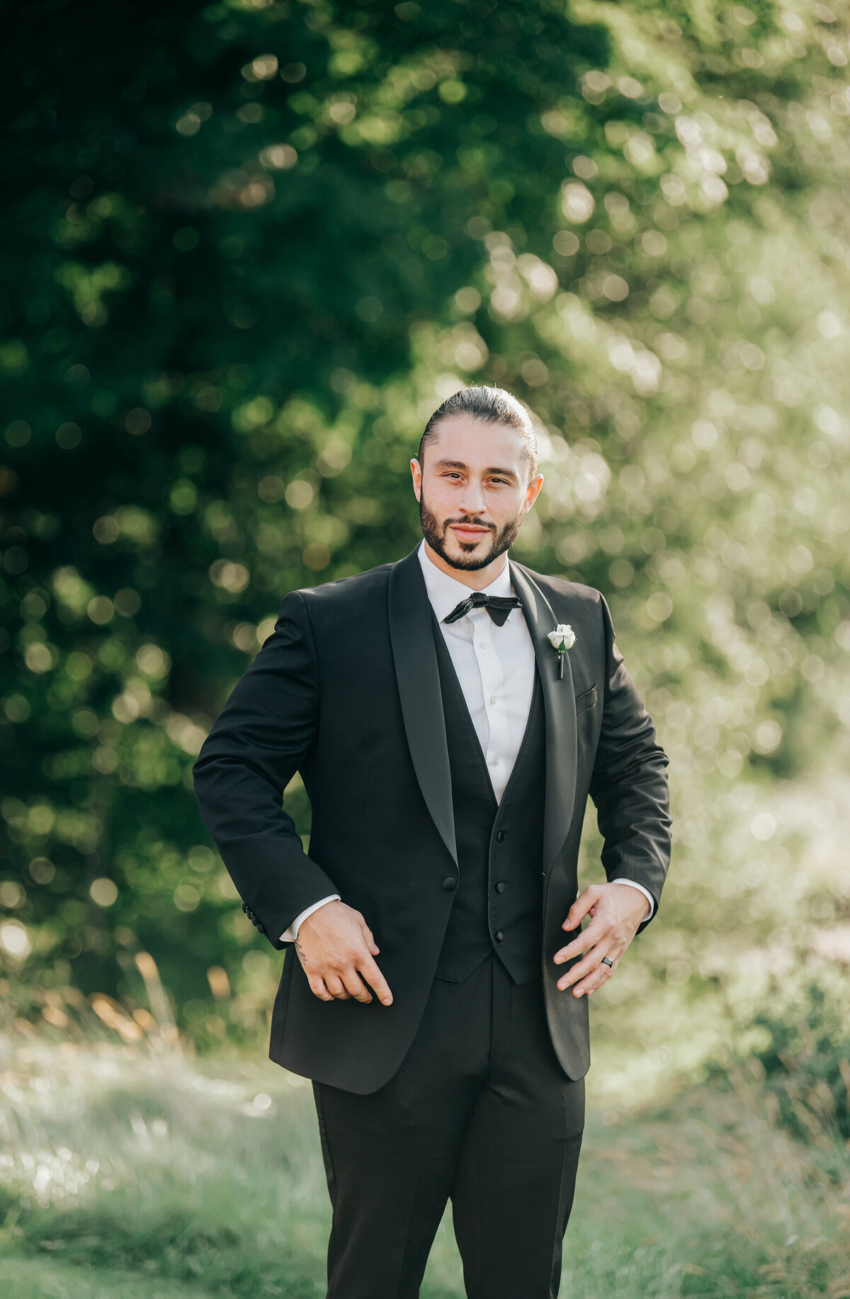 Groom posing for photos in his black tie attire on his Summer wedding day at the London Hunt Club