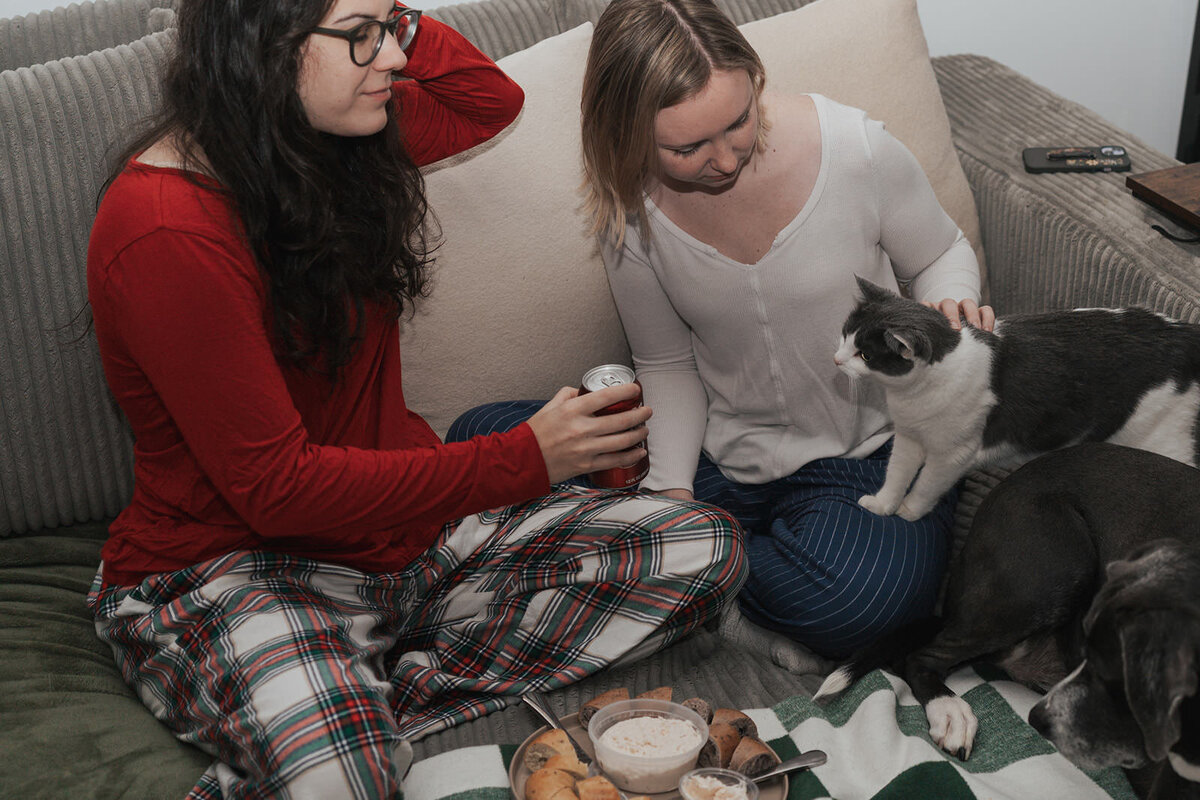 Two women hold their cat in their lap 