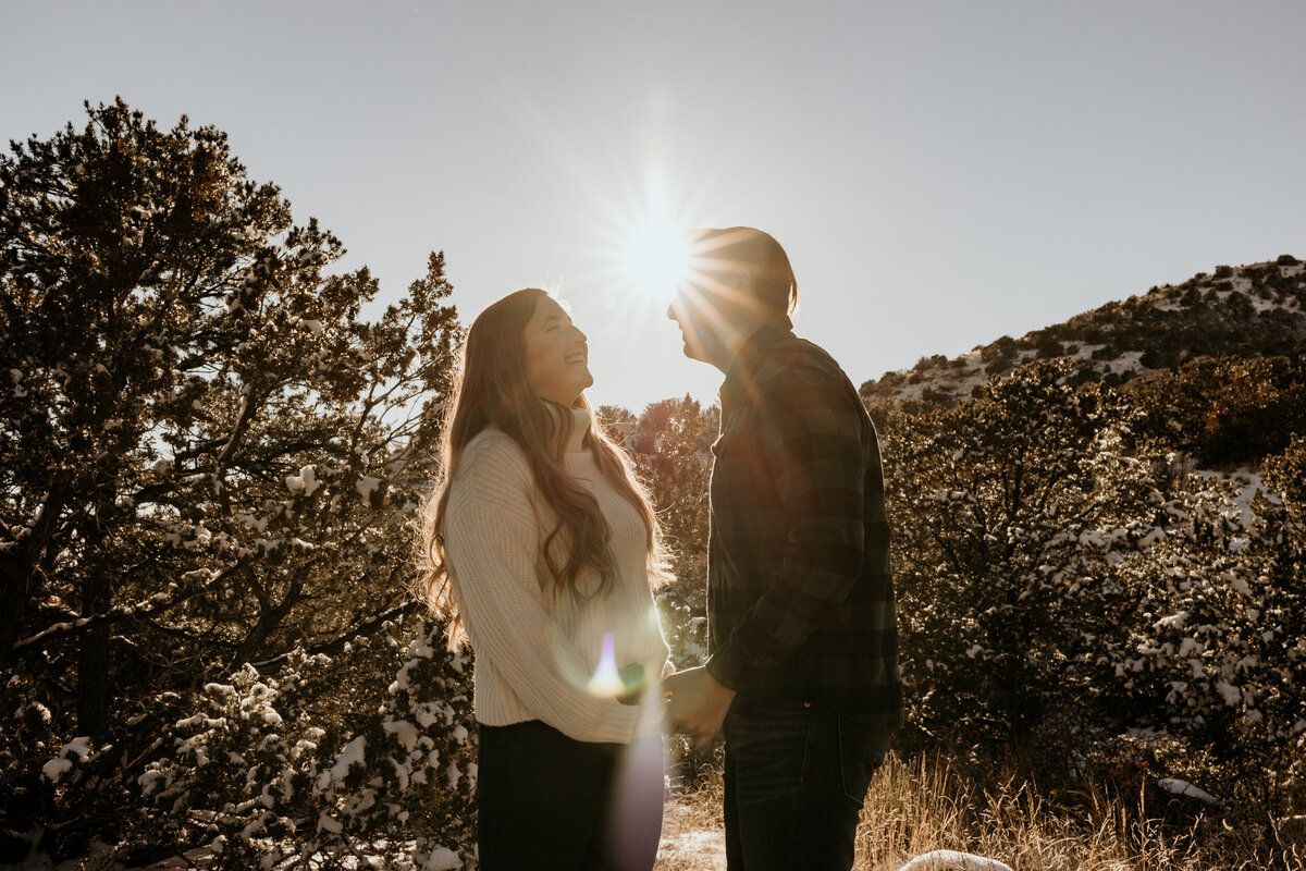 couple holding hands and laughing  with a sun flare