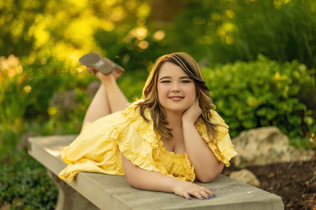 A girl from Waukesha West High School lays on a concrete bench at Lapham Peak for her senior portraits.