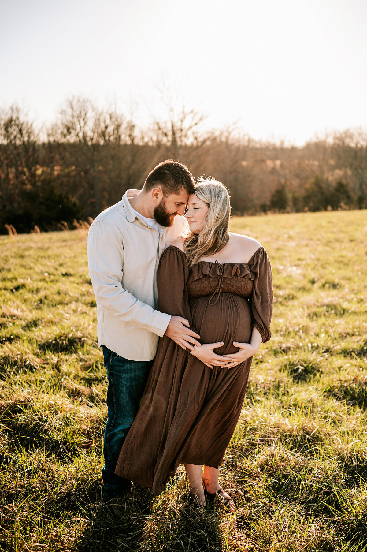 pregnant couple leaning into each other, nose to nose, while mother is holding her pregnant belly