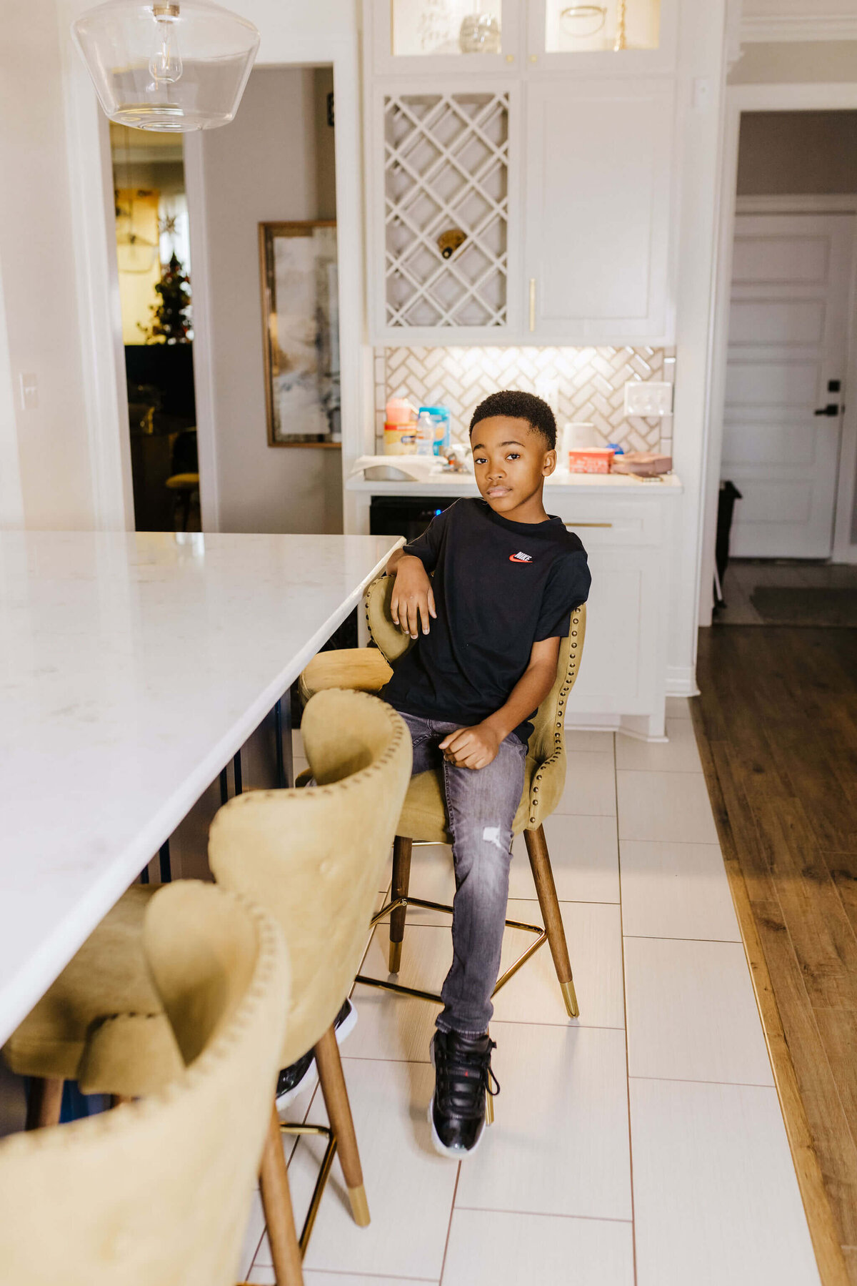 teenage son sitting at kitchen bar in yellow barstool during in home lifestyle photography session