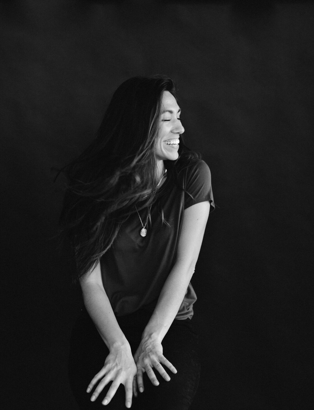 woman laughs, hair movement, dark black backdrop, studio brand photography