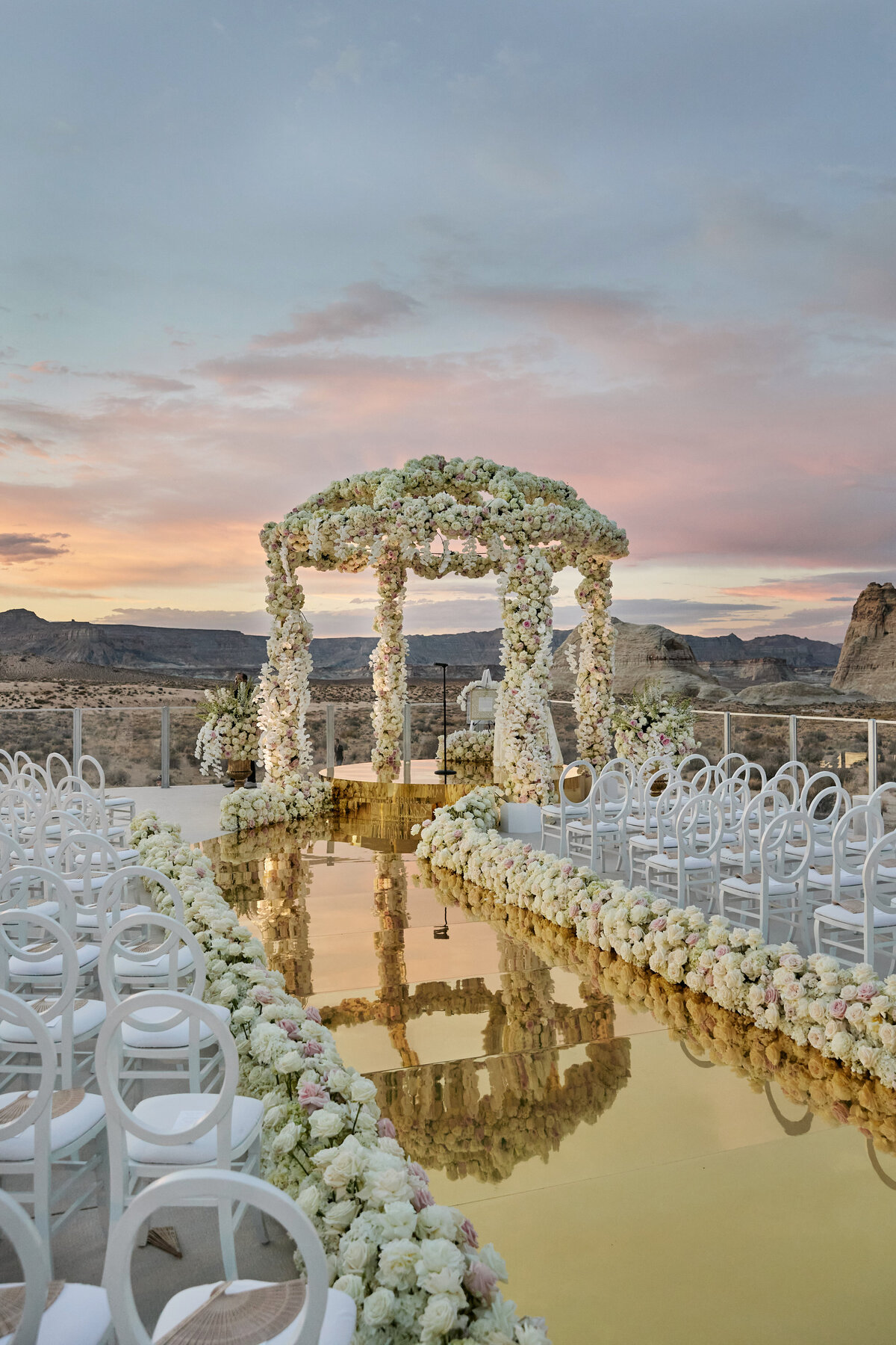 Chuppah at amangiri Utah with golden aisle and white flowers and chairs