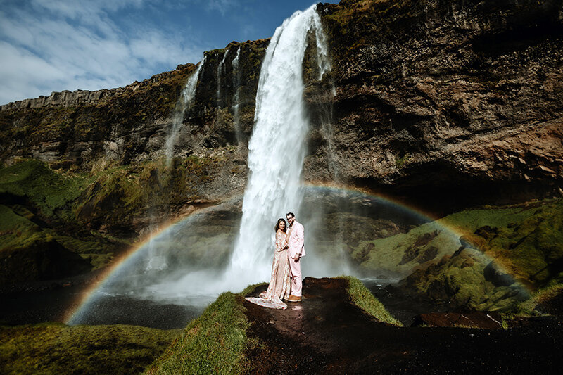 married couple in front of a waterfall in iceland on their wedding day